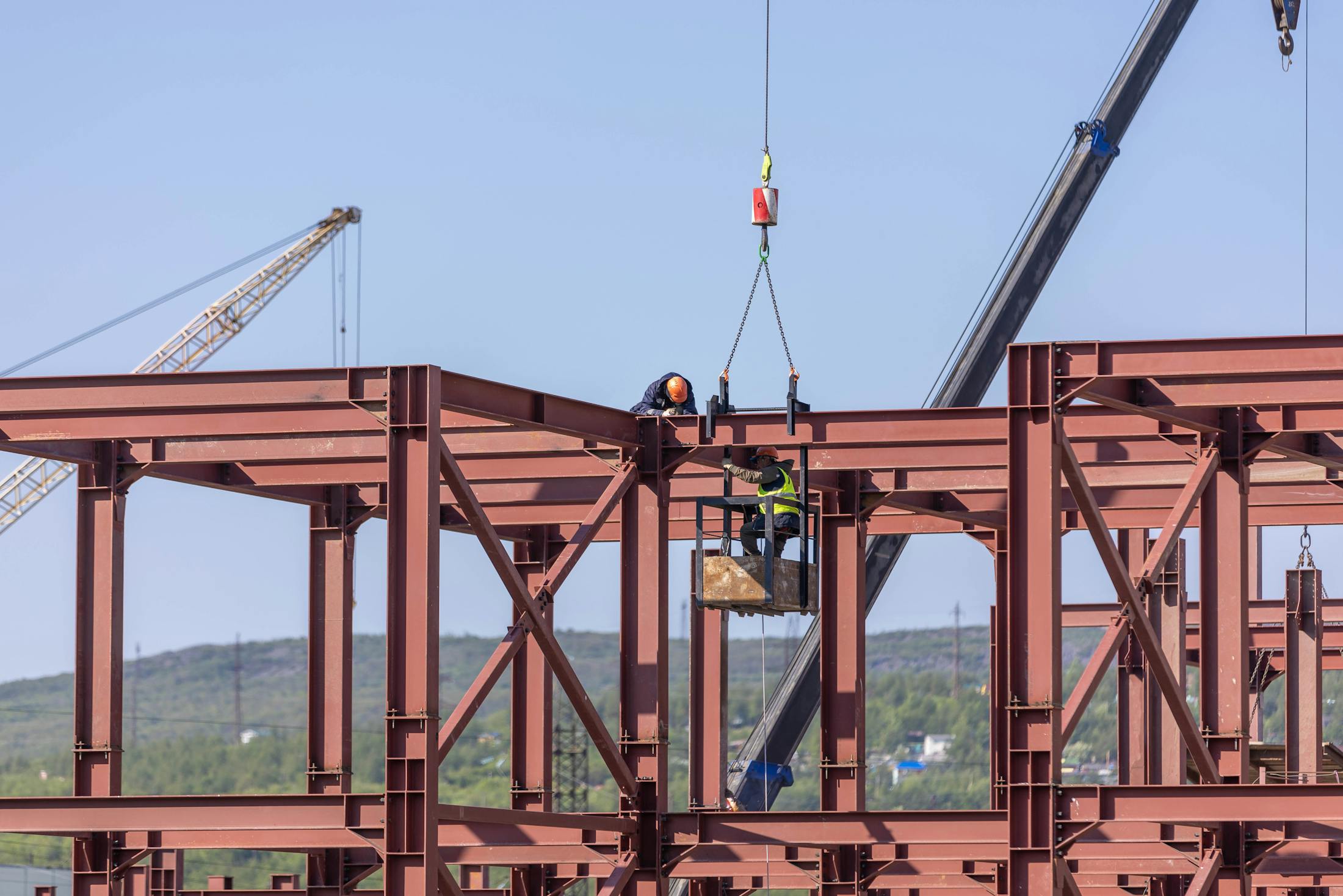 Structural steel frame being erected on a commercial site with cranes